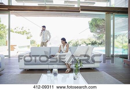Couple using cell phone and laptop in living room View Large Photo Image Stock Image - Couple using cell phone and laptop in living room. Fotosearch