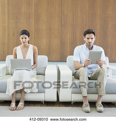 Couple using digital tablet and laptop in armchairs View Large Photo Image Stock Image - Couple using digital tablet and laptop in armchairs. Fotosearch