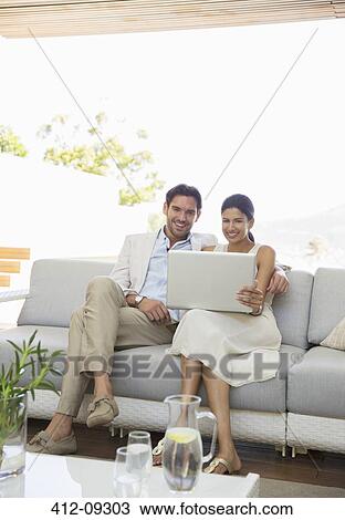 Couple using laptop together on sofa View Large Photo Image Stock Image - Couple using laptop together on sofa. Fotosearch