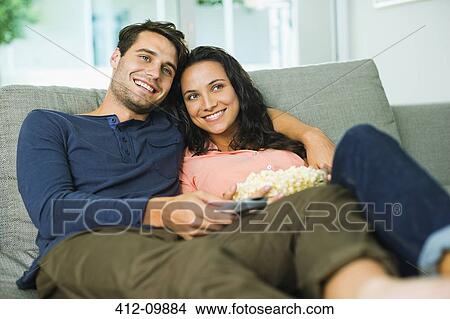 Couple watching television on sofa View Large Photo Image Picture - Couple watching television on sofa. Fotosearch