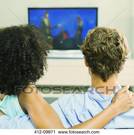 Couple watching television on sofa View Large Photo Image Stock Image - Couple watching television on sofa. Fotosearch
