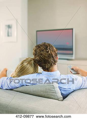 Stock Photo - Couple watching television on sofa. Fotosearch