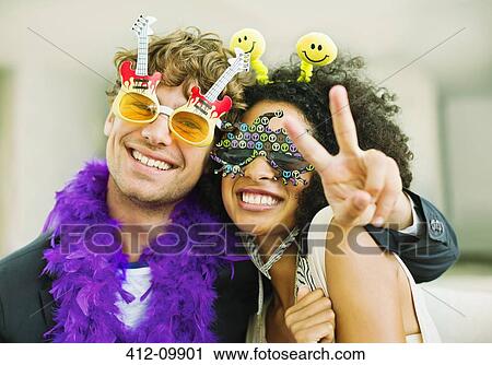 Stock Image - Couple wearing decorative glasses at party. Fotosearch