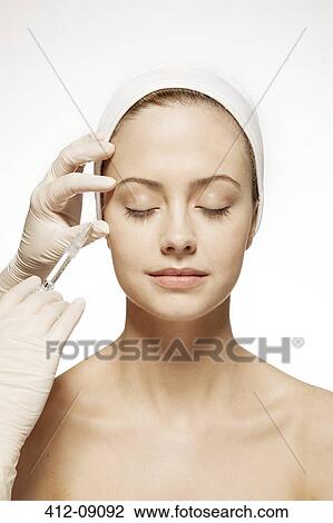Stock Image - Doctor injecting botox into woman's face. Fotosearch