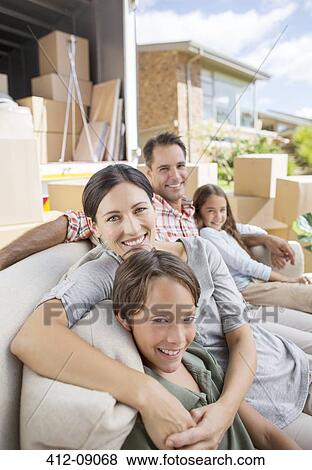 Stock Photo - Family sitting on sofa near moving van in driveway. Fotosearch