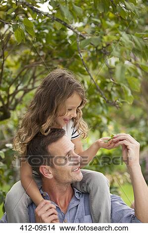 Picture - Father carrying daughter on shoulders outdoors. Fotosearch