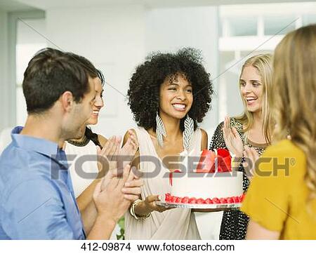 Picture - Friends clapping around woman with birthday cake. Fotosearch