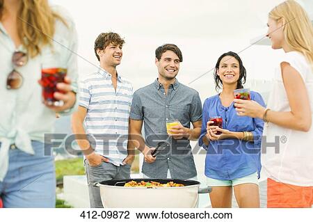Friends enjoying drinks at barbecue View Large Photo Image Stock Image - Friends enjoying drinks at barbecue. Fotosearch