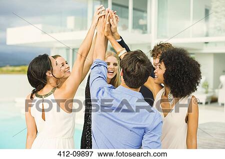 Friends high fiving at poolside View Large Photo Image Stock Photo - Friends high fiving at poolside. Fotosearch