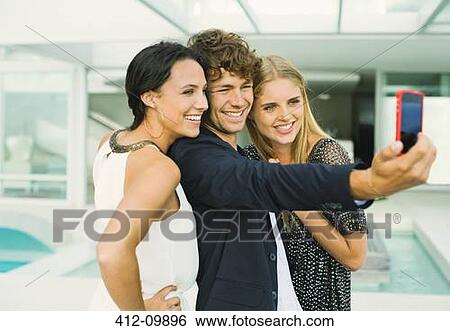 Stock Photograph - Friends taking self-portrait at poolside. Fotosearch