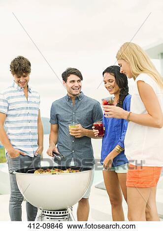 Stock Photograph - Friends talking around barbecue. Fotosearch
