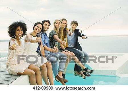 Friends toasting champagne flutes on footbridge over swimming pool View Large Photo Image Stock Photo - Friends toasting champagne flutes on footbridge over swimming pool. Fotosearch