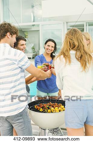Stock Image - Friends toasting cocktails at barbecue. Fotosearch