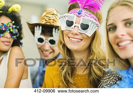Friends wearing decorative glasses at party View Large Photo Image Stock Photograph - Friends wearing decorative glasses at party. Fotosearch