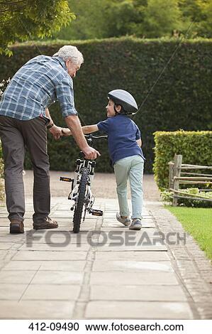 Grandfather and grandson pushing bicycle on sidewalk View Large Photo Image Stock Image - Grandfather and grandson pushing bicycle on sidewalk. Fotosearch