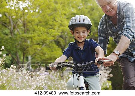 Grandfather teaching grandson to ride bicycle View Large Photo Image Stock Image - Grandfather teaching grandson to ride bicycle. Fotosearch