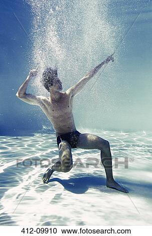 Stock Image - Man posing underwater in swimming pool. Fotosearch