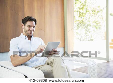 Man using digital tablet in armchair View Large Photo Image Stock Photo - Man using digital tablet in armchair. Fotosearch
