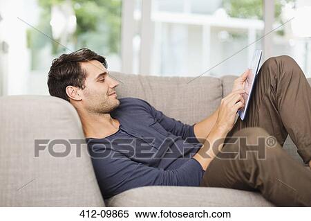 Man using digital tablet on sofa View Large Photo Image Stock Photography - Man using digital tablet on sofa. Fotosearch