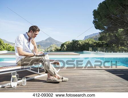 Man using laptop at poolside View Large Photo Image Stock Image - Man using laptop at poolside. Fotosearch