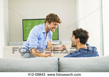 Stock Image - Men cheering and watching soccer game. Fotosearch