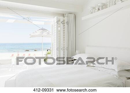 Stock Image - Modern bedroom overlooking beach and ocean. Fotosearch