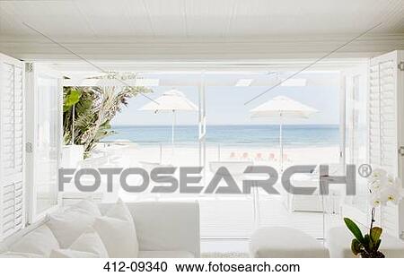 Stock Image - Modern living room overlooking beach and ocean. Fotosearch