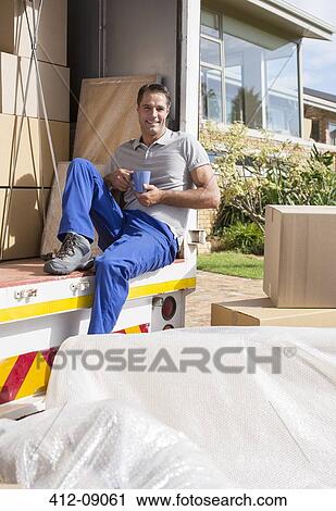 Stock Image - Mover enjoying cup of coffee in back of moving van. Fotosearch