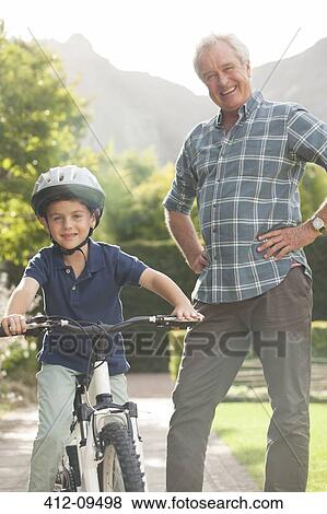 Older man teaching grandson to ride bicycle View Large Photo Image Stock Photo - Older man teaching grandson to ride bicycle. Fotosearch