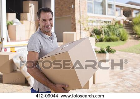Portrait of man carrying cardboard box from moving van View Large Photo Image Picture - Portrait of man carrying cardboard box from moving van. Fotosearch