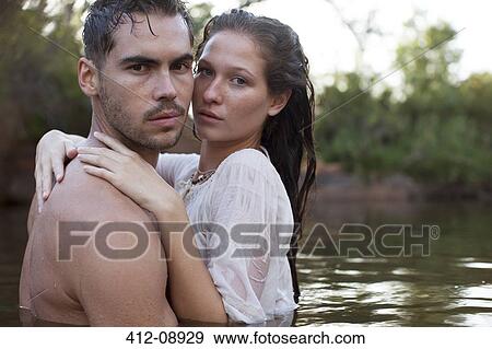 Portrait of serious couple hugging in river View Large Photo Image Stock Photo - Portrait of serious couple hugging in river. Fotosearch