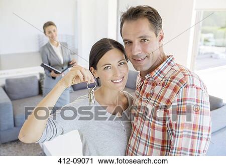 Stock Image - Portrait of smiling couple holding house keys. Fotosearch