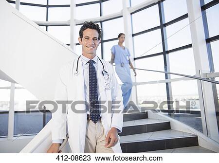 Stock Image - Portrait of smiling doctor on staircase in hospital. Fotosearch