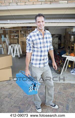 Portrait of smiling man holding toolbox outside garage View Large Photo Image Stock Image - Portrait of smiling man holding toolbox outside garage. Fotosearch