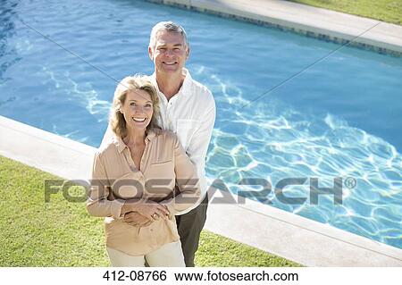 Portrait of smiling senior couple at poolside View Large Photo Image Stock Photograph - Portrait of smiling senior couple at poolside. Fotosearch