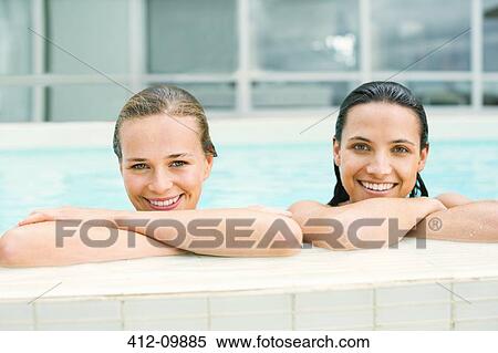 Stock Photography - Portrait of smiling women at edge of swimming pool. Fotosearch