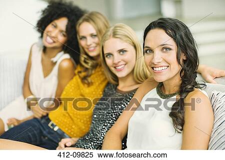 Stock Photography - Portrait of smiling women on sofa. Fotosearch
