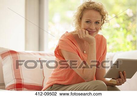 Portrait of woman using digital tablet on sofa View Large Photo Image Stock Image - Portrait of woman using digital tablet on sofa. Fotosearch