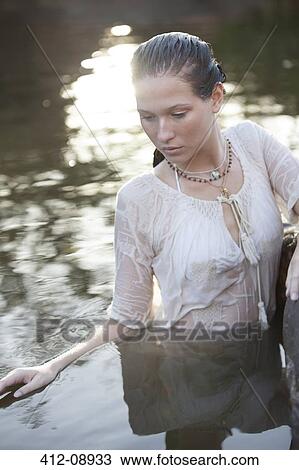 Stock Image - Serene woman standing in river. Fotosearch