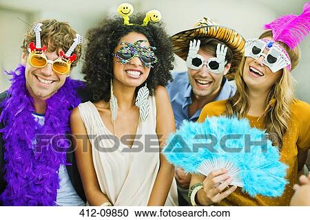 Stock Image - Smiling friends wearing silly glasses. Fotosearch