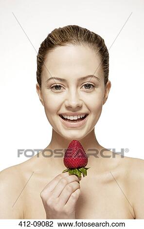 Stock Image - Smiling woman eating strawberry. Fotosearch