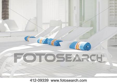 Striped towels rolled up on white lounge chairs View Large Photo Image Stock Photo - Striped towels rolled up on white lounge chairs. Fotosearch