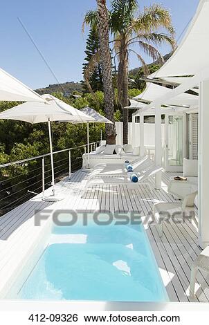 Swimming pool and lounge chairs on patio View Large Photo Image Stock Photograph - Swimming pool and lounge chairs on patio. Fotosearch