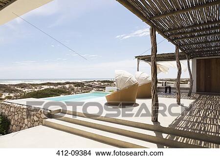 Swimming pool, chairs and patio of modern house View Large Photo Image Picture - Swimming pool, chairs and patio of modern house. Fotosearch
