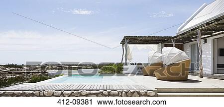 Swimming pool, chairs and patio of modern house View Large Photo Image Stock Image - Swimming pool, chairs and patio of modern house. Fotosearch