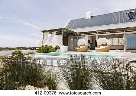 Swimming pool, chairs and patio of modern house View Large Photo Image Stock Photograph - Swimming pool, chairs and patio of modern house. Fotosearch