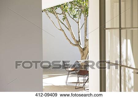 Table, chairs and tree in courtyard View Large Photo Image Stock Photo - Table, chairs and tree in courtyard. Fotosearch