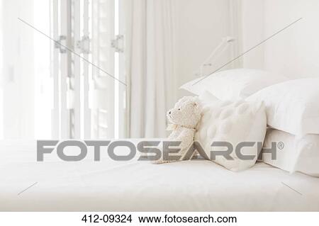 Teddy bear and pillows on white bed View Large Photo Image Picture - Teddy bear and pillows on white bed. Fotosearch