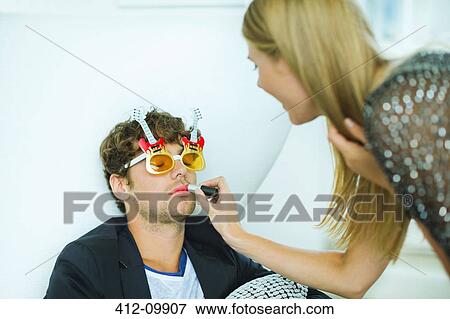 Woman applying lipstick to sleeping man at party View Large Photo Image Stock Photo - Woman applying lipstick to sleeping man at party. Fotosearch