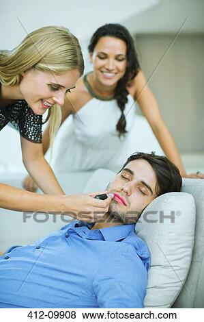 Woman applying lipstick to sleeping man View Large Photo Image Stock Photo - Woman applying lipstick to sleeping man. Fotosearch